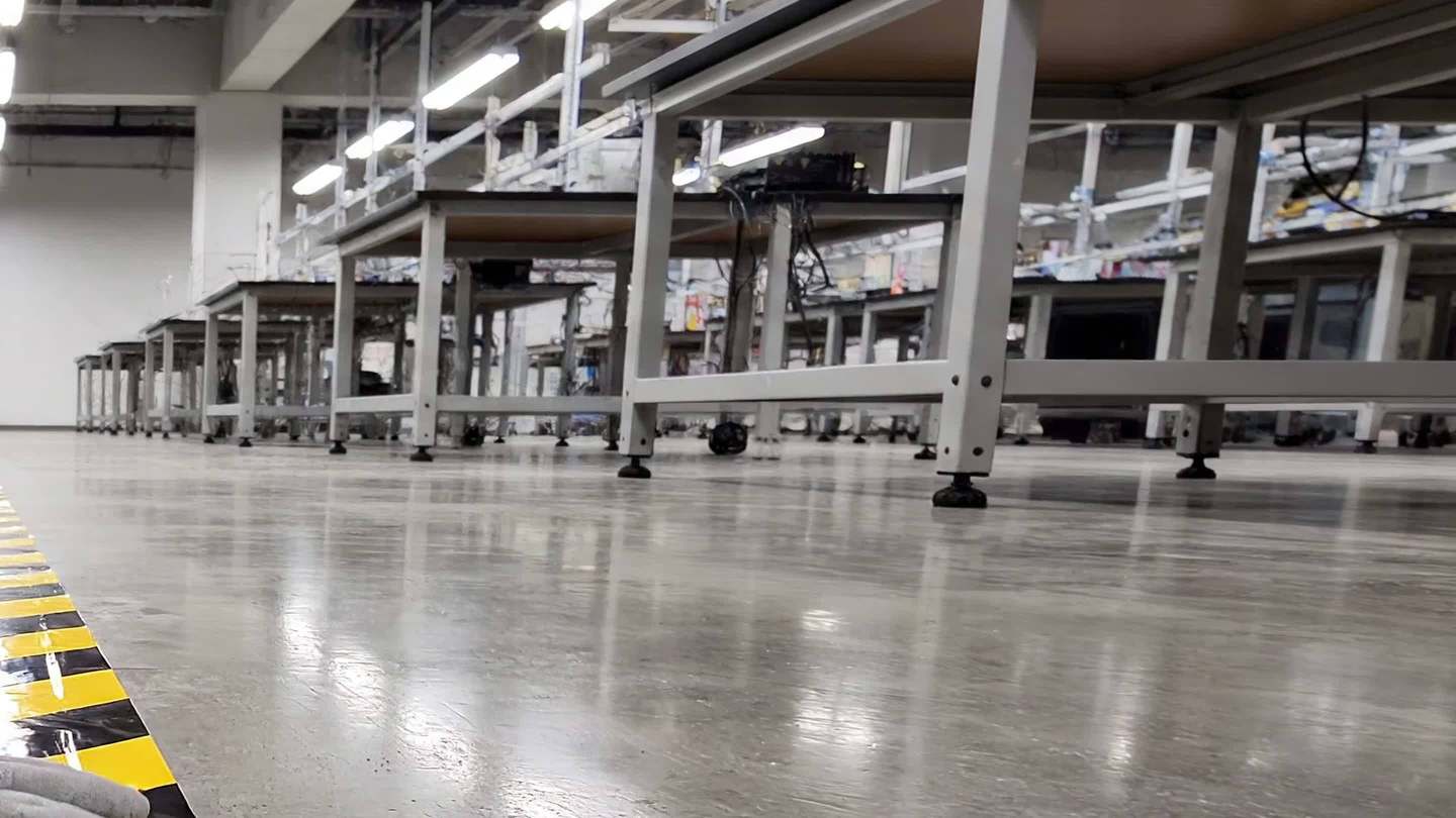 Workbenches standing on a glossy floor beside yellow and black boundary tape